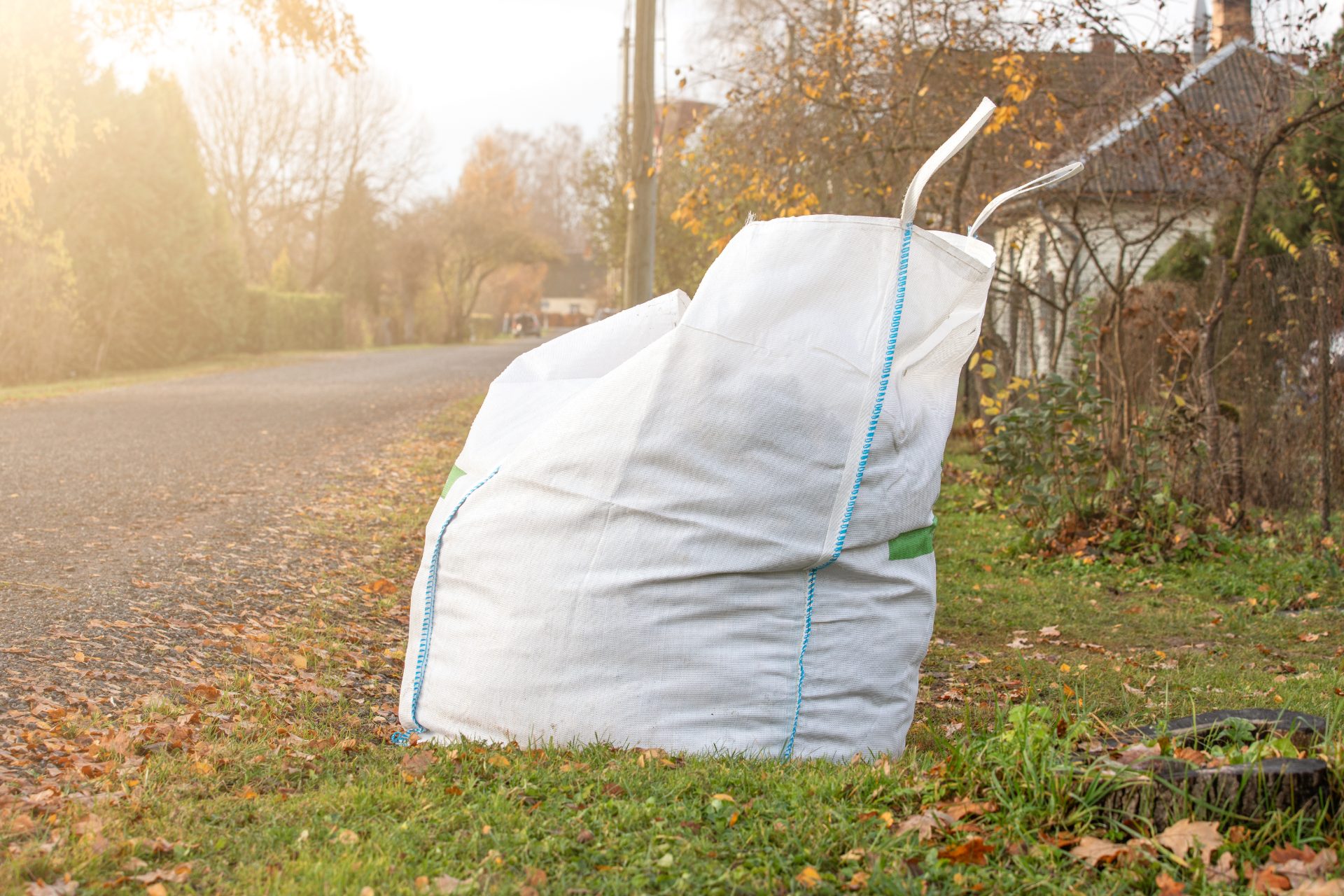 Big white bag filled with organic green garden waste after gardening.